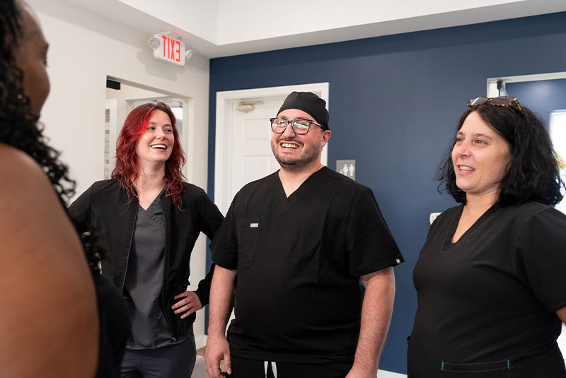staff and doctor s smiling brightly while greeting dental patient within the dental center