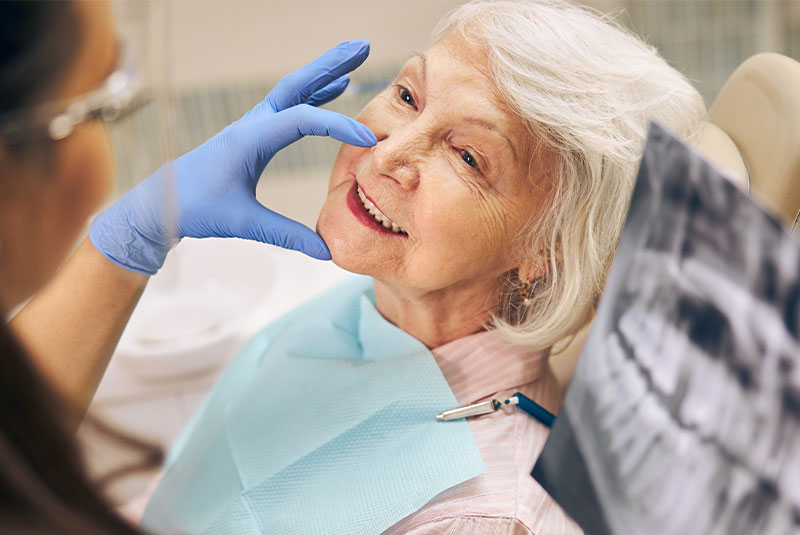 mature patient smiling while being examined by the dental practice staff memeber